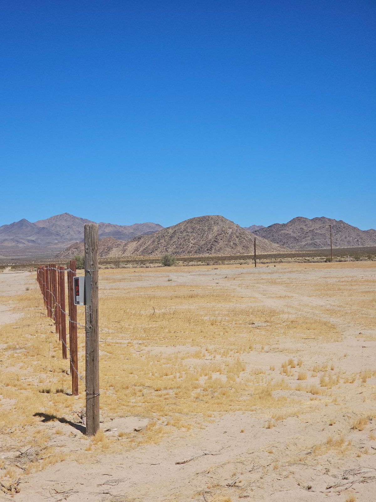 Fence line with service equipment mounted on a post, mountains behind