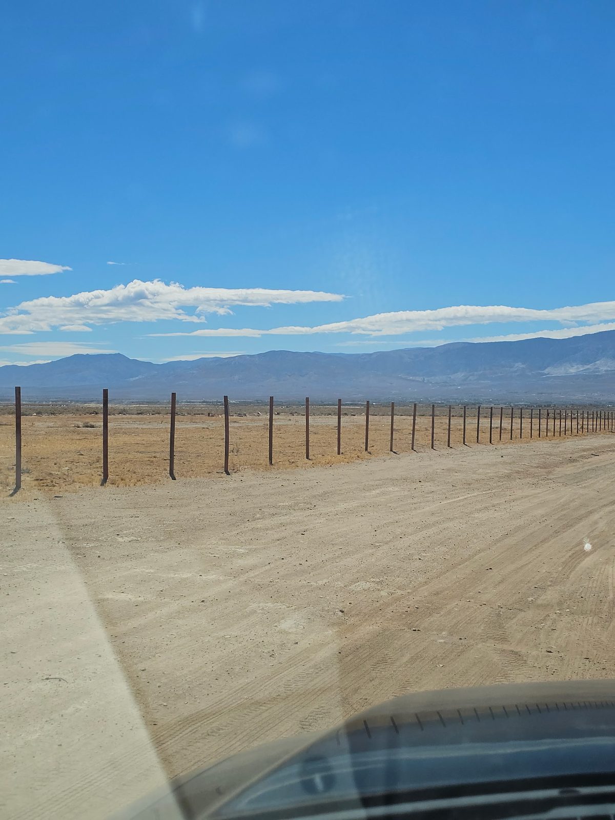 Graded road running along the fenced frontage of the property